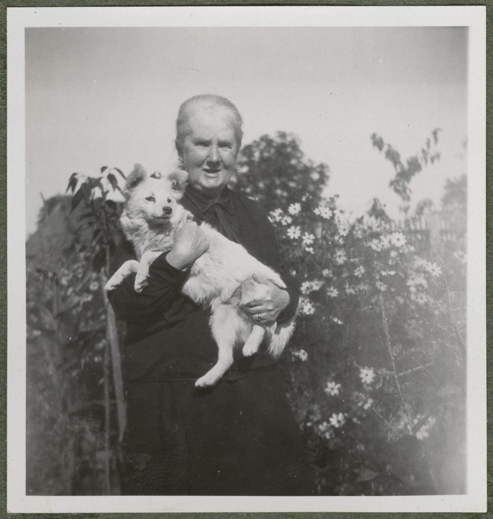 Maria Kosińska w ogrodzie z psem na rękach, portret