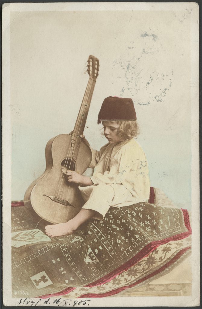 Chłopiec w fezie, z gitarą