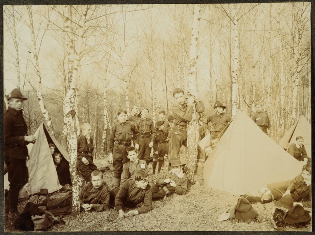 Grupa skautów przy namiotach.