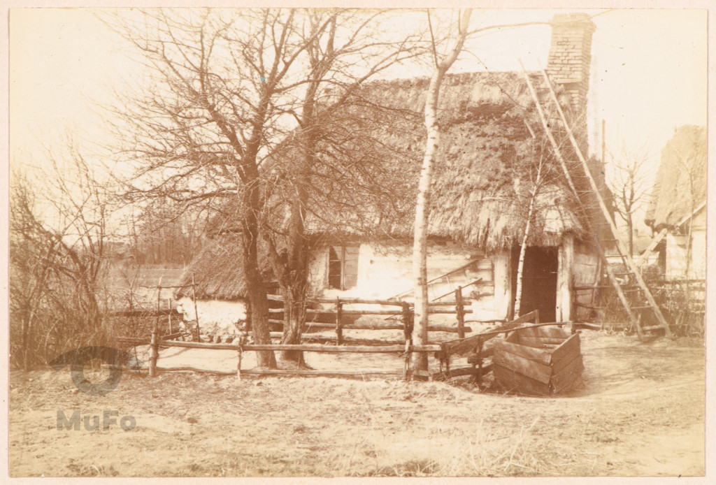 Drewniany dom (chata) kryty strzechą.