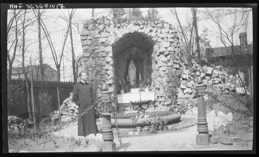 Ksiądz przed grotą z figurą Matki Boskiej