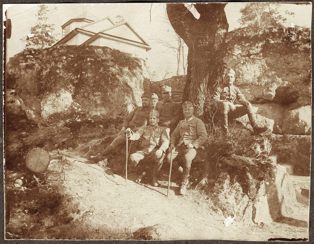 wojskowi  w mundurach armii austro-węgierskiej, portret zbiorowy w plenerze, na tle budowli z wieżą; fot. z albumu zw. temat. z frontem ros. w cz.I wojny świat.