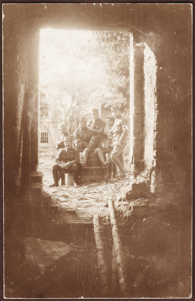 wojskowi  w mundurach armii austro-węgierskiej, portret zbiorowy w plenerze, przy beczce, widoczni w bramie budynku; fot. z albumu zw. temat. z frontem ros. w cz.I wojny świat.