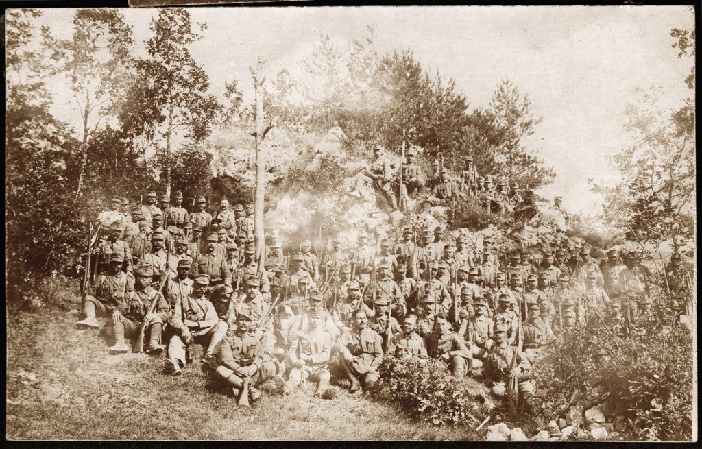 wojskowi ok. 100. os. siedzący na zboczu w mundurach armii austro-węgierskiej, portret zbiorowy w plenerze, fot. z albumu zw. temat. z frontem ros. w cz.I wojny świat.