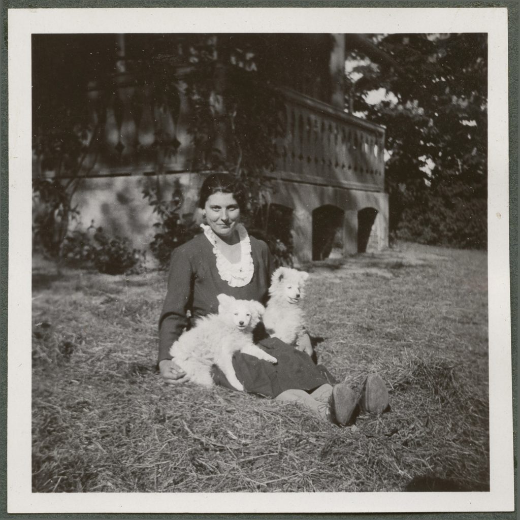 Młoda kobieta z białymi psami na kolanach, portret w plenerze