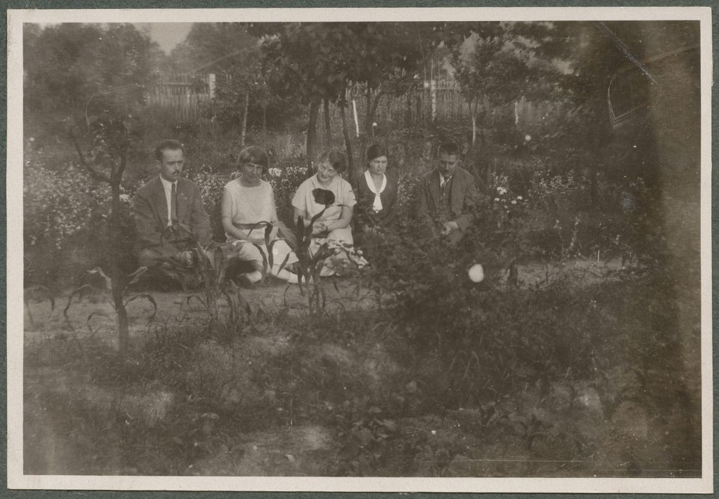 Grupa osób siedzących na ścieżce, scena w plenerze